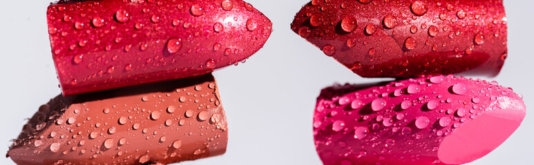 close up view of wet lipsticks isolated on white, panoramic shot