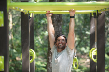 Obraz premium man doing abdominal exercise on horizontal bar in summer park