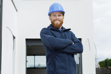 attractive builder outdoors with tablet and blueprints smiling at camera