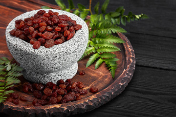 Close up of black raisins in a stone bowl, close up, dark background