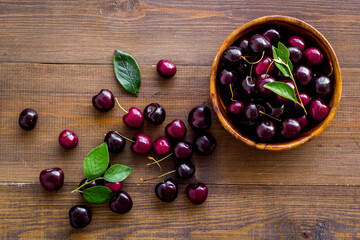 Red cherries with leaves in wooden bowl. Layout, berries background