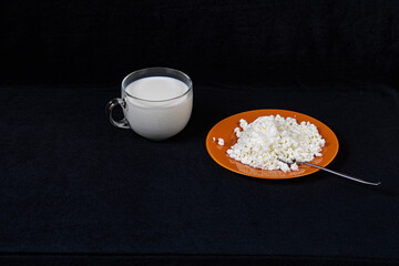 Glass mug with milk and saucer with cottage cheese with sour cream and sugar