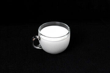 Mug with milk on a dark black background.