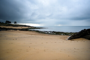 .A sandy beach on the shores of the ocean during stormy weather.