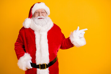 Portrait of his he nice funny cheerful cheery confident glad white-haired Santa demonstrating copy space ad advert isolated over bright vivid shine vibrant yellow color background