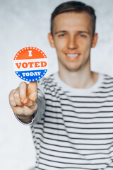 young man holding I voted today sticker button. elections in the United States. Copy Space. white blurred background. 