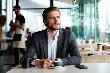 Young businessman in a suit drinking tea in a cafe