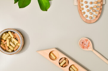 Herb in capsules in wooden bowl on pastel beige background. Beauty products for face and body skin care