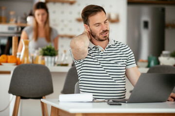 Young businessman having backache. Handsome man working at home.