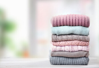 Stack of knitted textured clothing on table.Colorful winter clothes,warm apparel.Heap of knitwear. - obrazy, fototapety, plakaty
