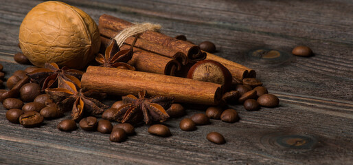 Cinnamon, anise stars, walnut, coffee grains on wooden background.