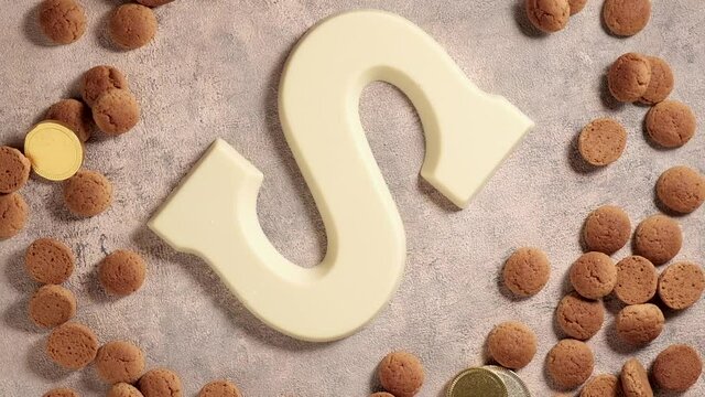 Rotation of kruidnoten, traditional sweets, strooigoed and white chocolate letter S. Background for Dutch holiday Sinterklaas. St. Nicholas day concept. FullHD video, top view