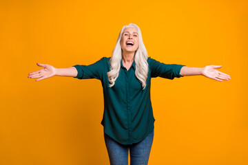 Hug me Photo of cheerful white haired grandma lady spread open arms meet grandchildren airport bus train station wear green shirt jeans isolated vivid yellow color background - obrazy, fototapety, plakaty