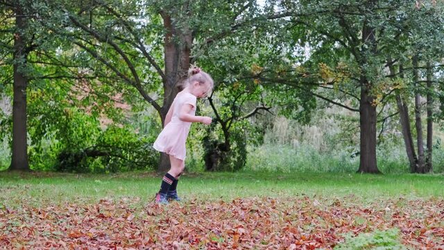 cheerful and smiling girl in a tutu dancing outdoor in the park on fallen leaves