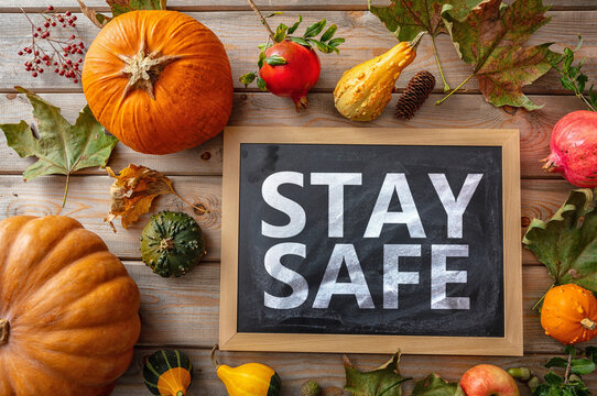 Stay safe message and thanksgiving pumpkins against wooden background. COVID 19 days