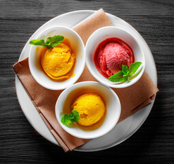 various ice cream desserts with mint leaf on black wooden table
