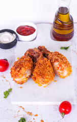 Delicious homemade crispy fried chicken with sauces on white marble background