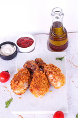 Delicious homemade crispy fried chicken with sauces on white marble background