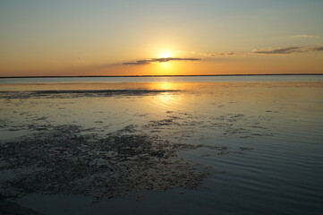 A sunny path from the setting sun on the calm water of the estuary.   