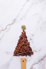 New year symbol: xmas tree made from red hot chilli peppers on marble background. Culinary christmas card with space for text top view.