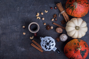 Pumpkins and cup of coffee on dark table, top view. Autumn  breakfast background