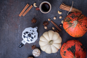 Pumpkins and cup of coffee on dark table, top view. Autumn  breakfast background