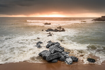 Fototapeta premium Sunset landscapes facing the sea with stones at Ericeira beach, Portugal
