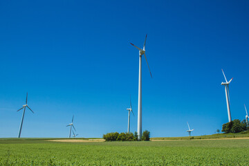 Fototapeta na wymiar Windmills on a German green field. Wind energy theme. Wind turbines producing electricity