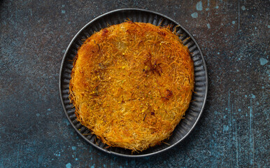 Künefe or knafeh - traditional Turkish dessert pastry made of filo filled with cheese and syrup. Popular Middle Eastern dessert, top view