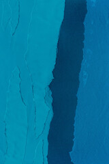 Blue torn paper collage close-up. Texture made from various paper and cardboard parts. Damaged old paper background. Vintage blank wallpaper. Material design backdrop.