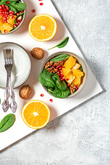 Fototapeta na wymiar Bright fruit salad and ingredients on the table top view. Salad of oranges, pomegranates, spinach and nuts in a bowl on a white background. Healthy diet food, vegetarian food. Copy space