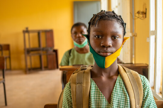 School Pupil's Sitting In Class, Wearing Face Masks, And Observing Physical Distancing