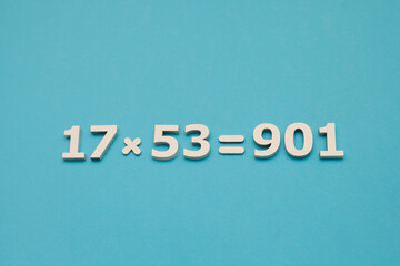 An example of multiplying two natural numbers with the correct answer to the task. White numbers are on a blue background. View from above.