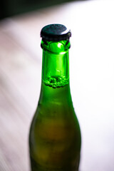 Blond beer on a green bottle closed on a wooden background