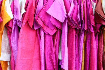 Fototapeta premium Colorful red pink gradient shirts cloths dress hanging on hangers display outdoor