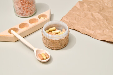 Herb in capsules in wooden bowl on pastel beige background. Beauty products for face and body skin care