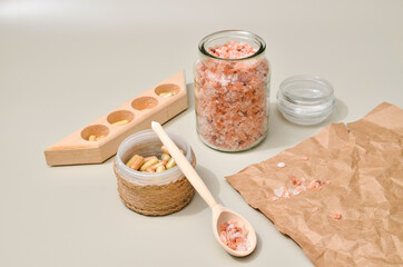Herb in capsules in wooden bowl on pastel beige background. Beauty products for face and body skin care