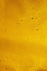 Close up view of cold drops on the glass of beer background. Texture of cooling alcohol drink with macro bubbles on the glass wall. Fizzing or floating up to top of surface. Golden colored.