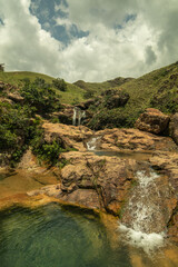 Manantial de agua con montañas que cubren su caída de agua.