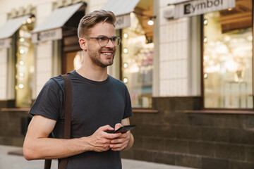 Young casual man using smart phone texting messages