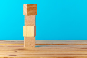 Stacked wooden blocks on wooden desk against blue background