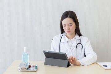  Coronavirus protection concept. Serious professional doctor wearing white coat and stethoscope holding modern touchscreen gadget using digital tablet computer at work.