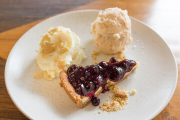 Blueberry cheese pie with  santol ice cream and whipped cream on a white plate.