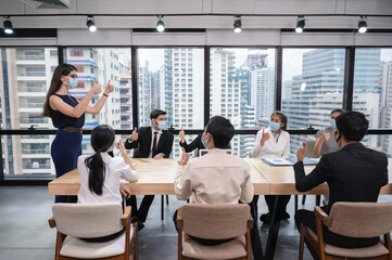 Group of multiethnic business people wearing face mask showing thumbs up and agree of business agreement during the meeting in new normal office