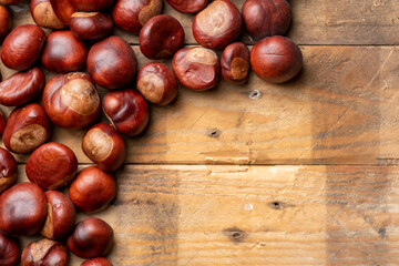 Photograph of Horse Chestnuts, Conkers arranged on a rustic wooden background shot from above with copy space. Autumn, fall, winter concept