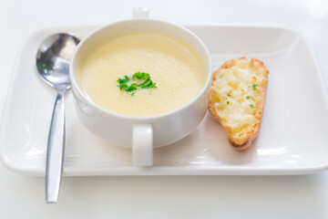 Delicious corn soup In a white bowl served with bread.