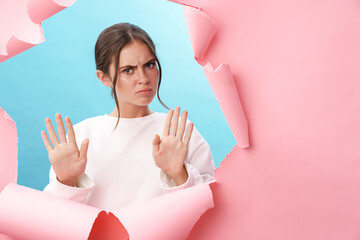 Caucasian young strict woman frowning and doing stop gesture with hands