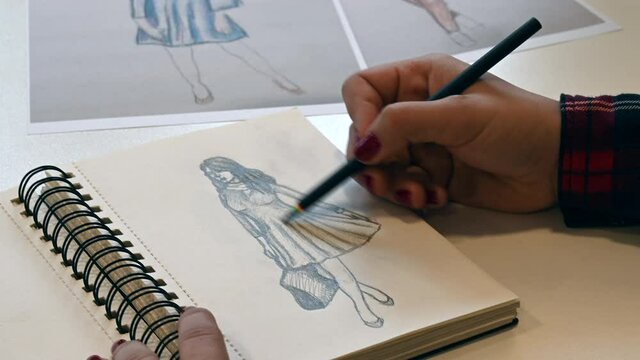 Close up shot of a female hand drawing new fashion design clothes line