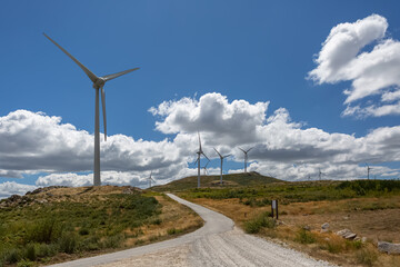 View of a wind turbines on top of mountains, cloudy sky as background