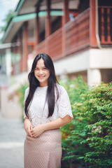 Young Asian women wearing Thai dress take pictures in a Thai-style house.